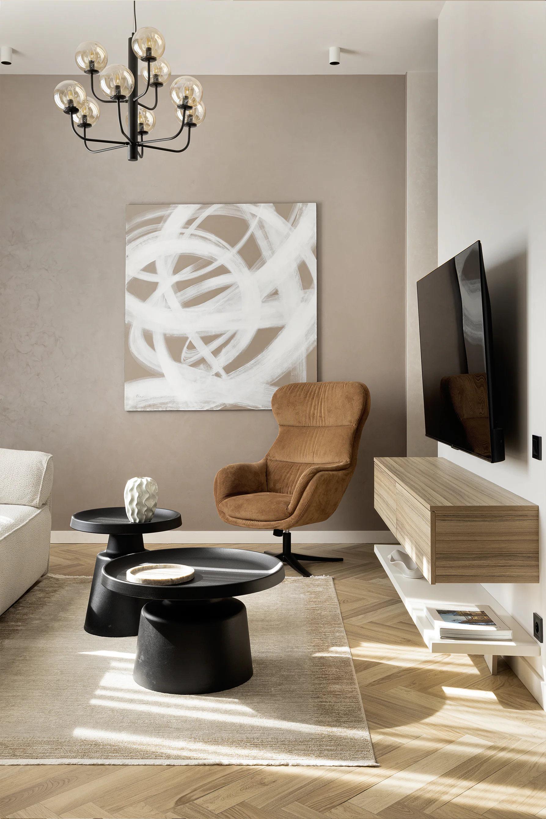 Arcus finished living/dining—black console with decor and mirror, view to beige sofa and round tables, herringbone floor, globe chandelier