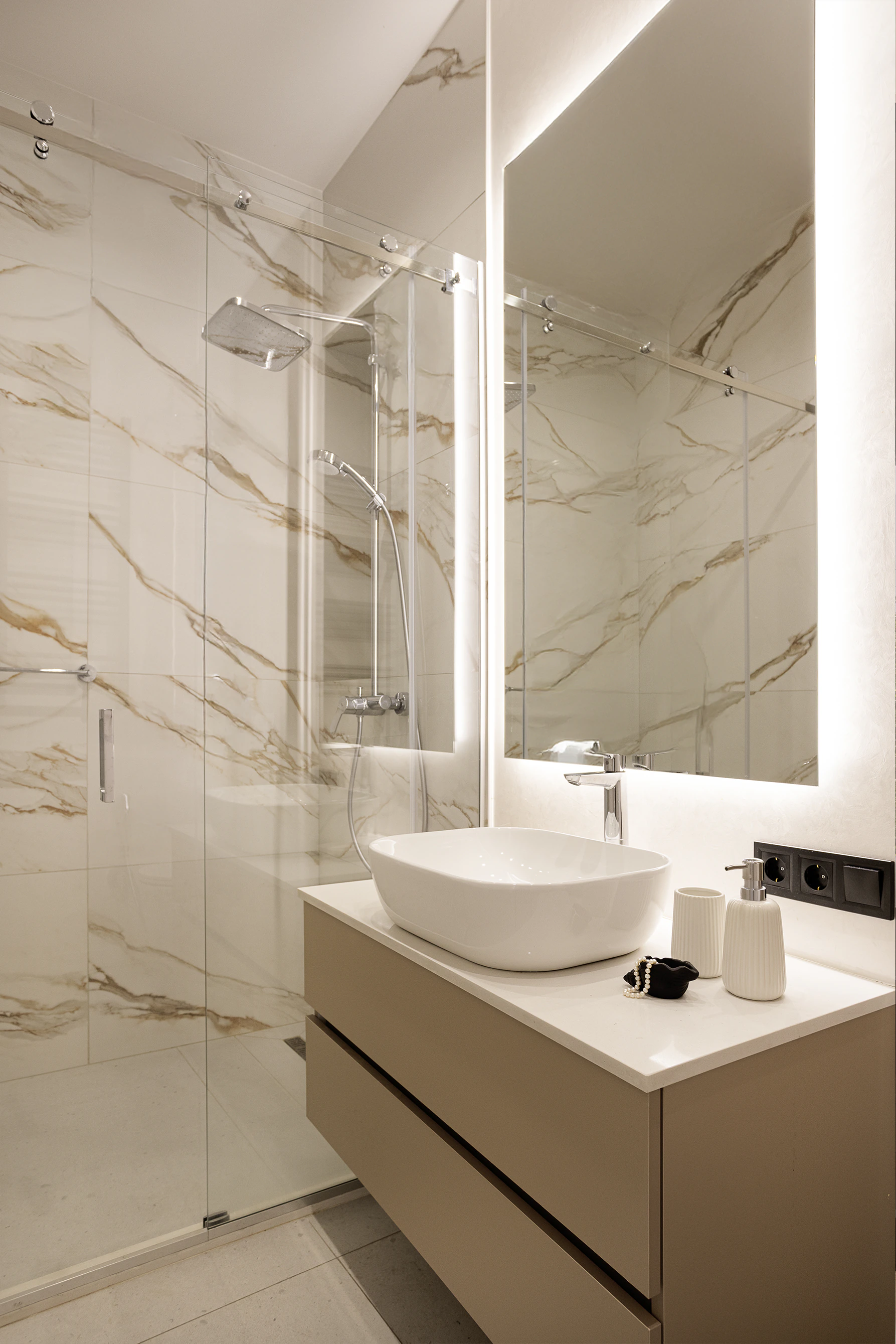 Bathroom—glass shower with marble-vein tiles, backlit mirror, vessel sink on floating vanity