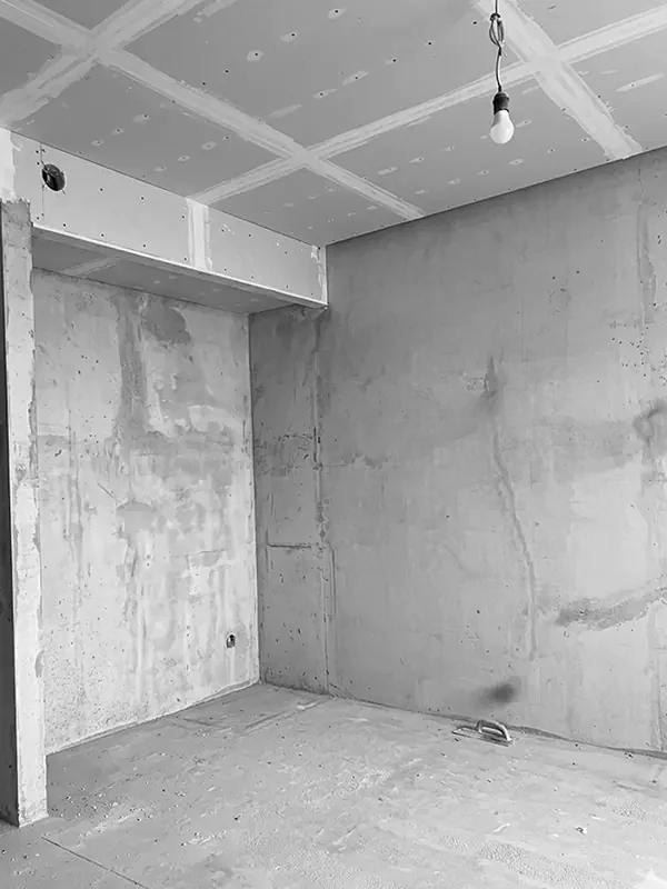 Квартира в резиденции Marriott в Батуми на этапе ремонта: пустая комната с потолком из гипсокартона и незавершёнными бетонными стенами