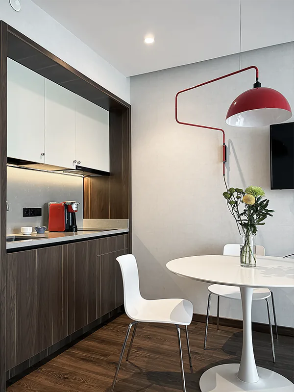 Интерьер частной квартиры в Батуми с компактной встроенной кухней, обеденной зоной, тёмными деревянными фасадами и современной отделкой