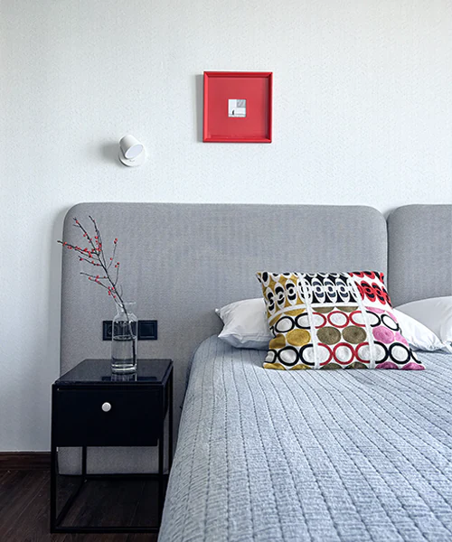 Bedroom in private apartments near 6 May Park in Batumi, featuring a gray upholstered headboard, black bedside table, decorative pillows, and modern minimalist decor in a new residential building with Marriott hotel