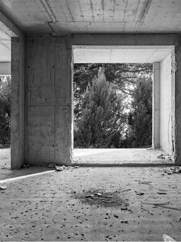 Raw concrete interior shell with large floor-to-ceiling window openings and an unfinished construction floor.