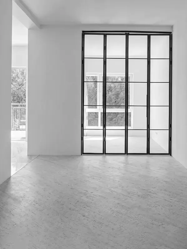Finished minimalist interior with black-framed glass partition doors, light flooring, and clean white walls.