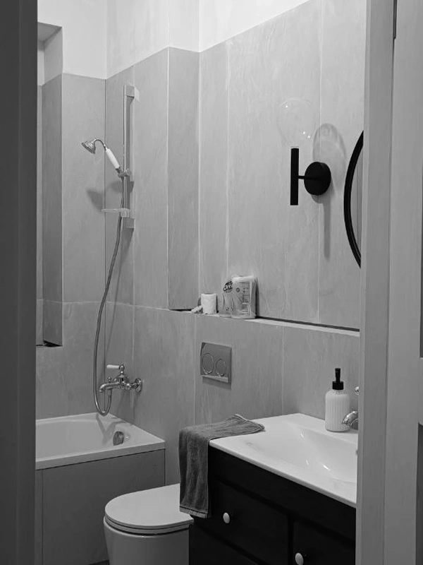 Renovation progress showing tiled bathroom with new bathtub, fixtures, and lighting installed