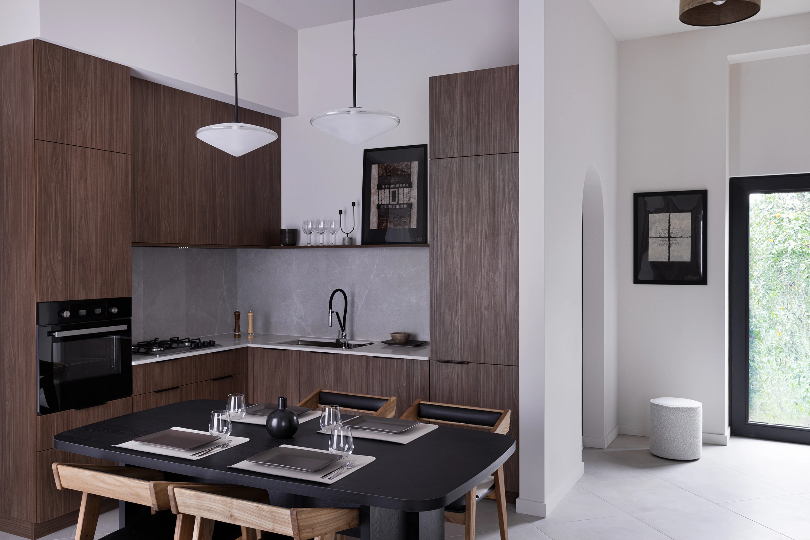 View of kitchen with dual pendant lights above a set dining table and wood cabinetry