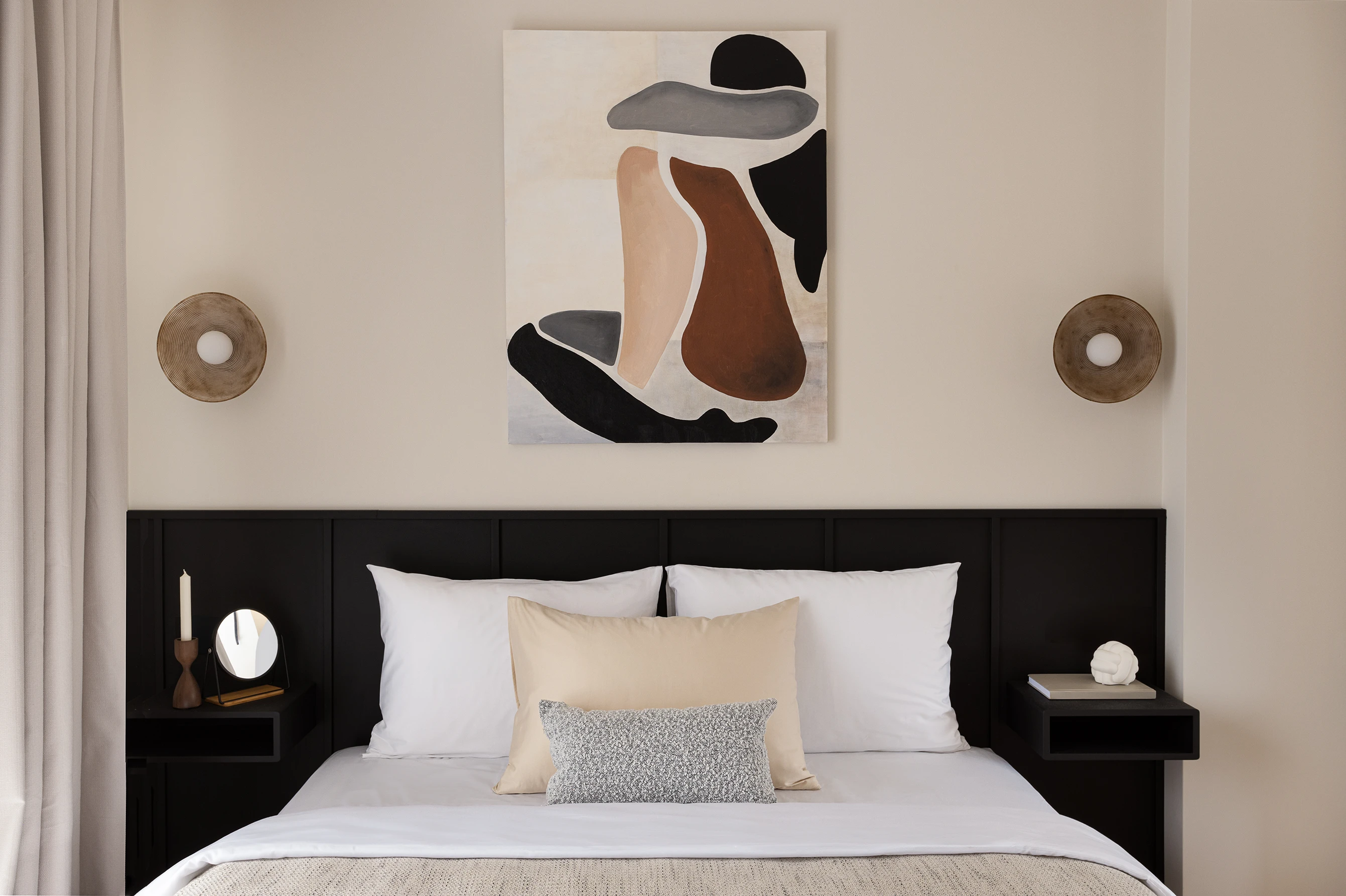 Frontal view of bed with abstract wall art and symmetrical sconces on either side