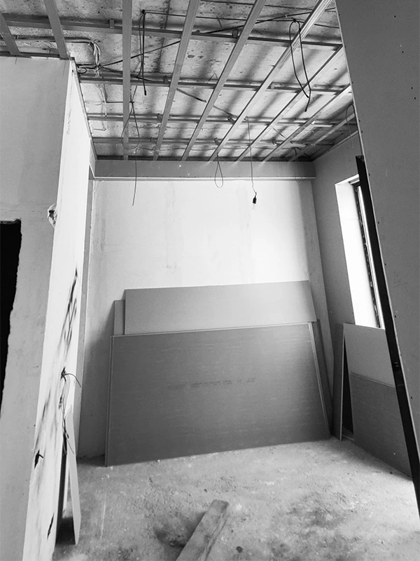 Early stage of Arcus renovation at Wabi-Sabi project, with exposed ceiling and stacked drywall sheets