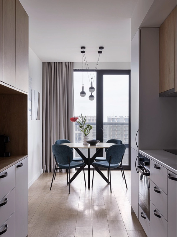 Finished dining area with round table, blue velvet chairs, and pendant lights — renovated by Arcus